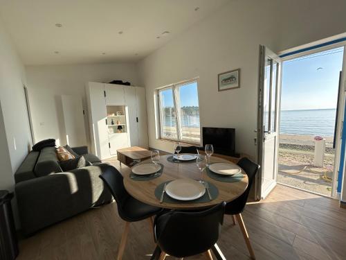un salon avec une table et des chaises et l'océan dans l'établissement La maison de la plage - Les Longueraies, à Plérin