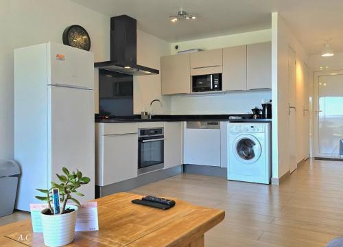 - une cuisine avec des appareils blancs et une table en bois dans l'établissement Les Embruns - Super Vue mer, refait à neuf avec parking privée à La Ciotat - BY AURAconciergerie, à La Ciotat