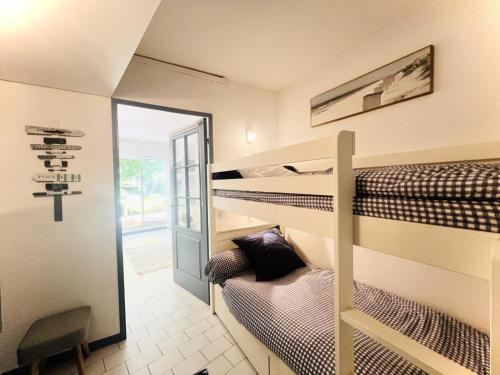 Cette chambre comprend 2 lits superposés et une croix sur le mur. dans l'établissement Villegiales Tee1 - 2 pièces cabine en rez de jardin avec piscine clim MAE-6313, à La Grande Motte
