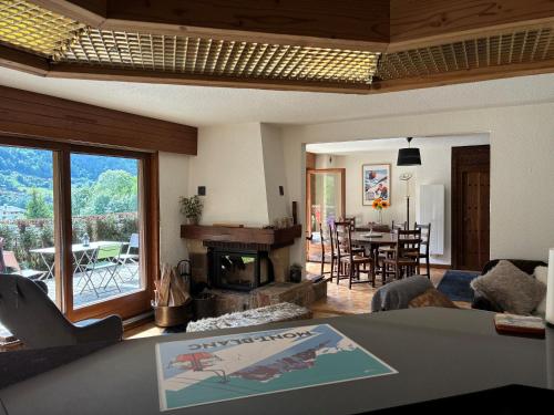a living room with a fireplace and a table and chairs at 3 Bed Apartment with Private Terrace, Communal Pool, Mont Blanc Views in Saint-Gervais-les-Bains