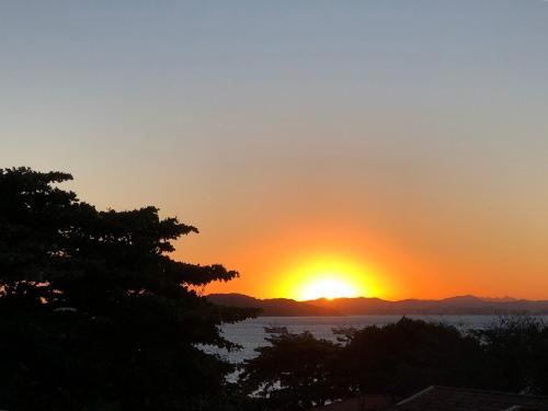 a sunset over the water with a tree at Pousada Casa de Cal y Canto in Penha