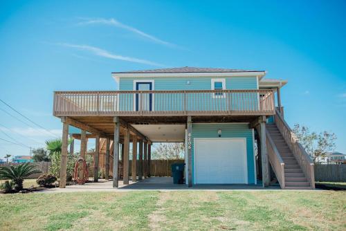 a blue house with a deck and a garage at Fly Away to Sea Bird Life is Better in Flip-Flops in Galveston