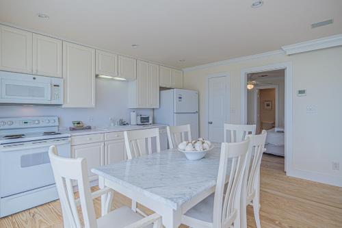 a kitchen with a table and chairs and a kitchen with white appliances at Original Margaritaville Beachfront Paradise Found. in Galveston