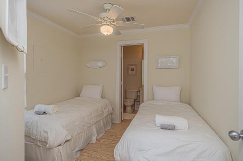two beds in a room with a ceiling fan at Original Margaritaville Beachfront Paradise Found. in Galveston