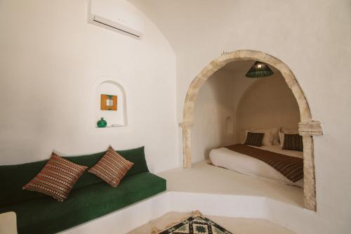 a bedroom with a bed and a green couch at Dar Naël in Houmt Souk
