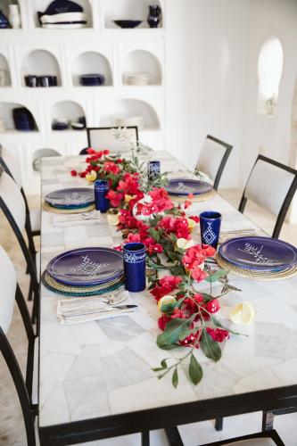 a table with blue plates and red flowers on it at Dar Naël in Houmt Souk