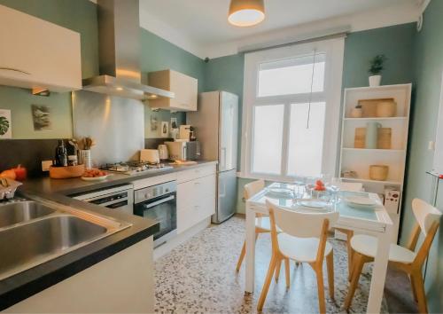 une cuisine avec une table, des chaises et un évier dans l'établissement La Maison du Parc - 2 chambres proche polyclinique, à Caen