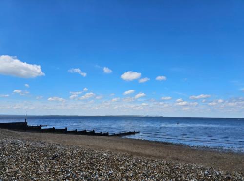 a beach with a blue sky and the ocean at Robins Sunset Holiday Home in Seasalter