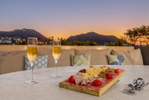 Cabo Marina Luxury Condo Jacuzzi & Terrace في كابو سان لوكاس: طبق من الطعام وكأسين من النبيذ على الطاولة