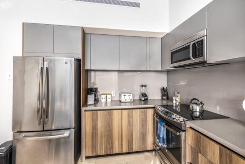 a kitchen with stainless steel appliances and wooden cabinets at Cabo Marina Luxury Condo Jacuzzi & Terrace in Cabo San Lucas
