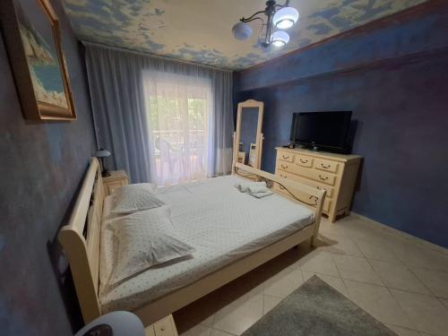 a bedroom with a bed and a dresser and a television at Apartament Onix in Neptun
