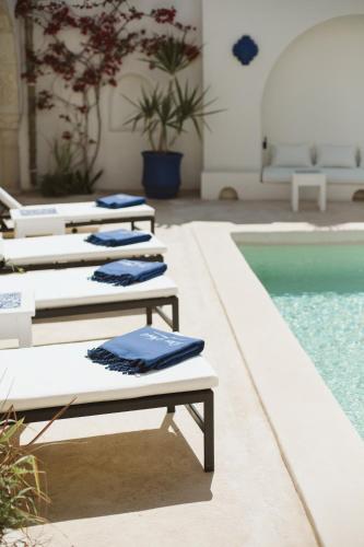 a row of lounge chairs next to a swimming pool at Dar Naël in Houmt Souk