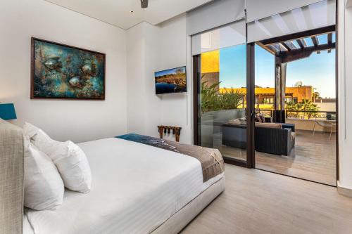 a bedroom with a bed and a balcony with a view at Hot Spot Overlooking Cabo Marina Private Terrace in Cabo San Lucas