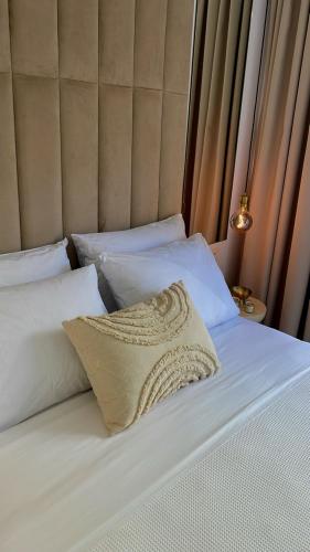 a bed with white sheets and a pillow on it at KLEOPATRA'S Luxury Suite in Preveza