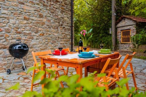 a wooden table with chairs and a grill in a yard at La Quiete del Pero Fiorito Villa in the Langhe in Monastero Bormida