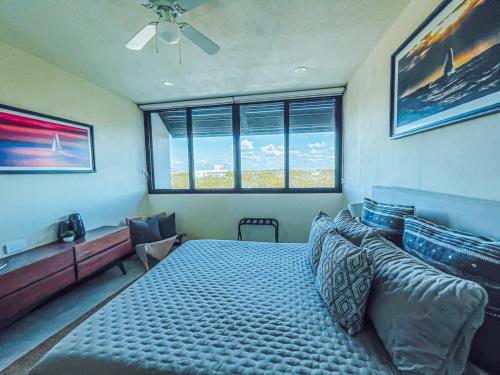 a bedroom with a bed and a large window at Sunrise 2BR Apt Steps from the Beach with Pool View in Holbox Island
