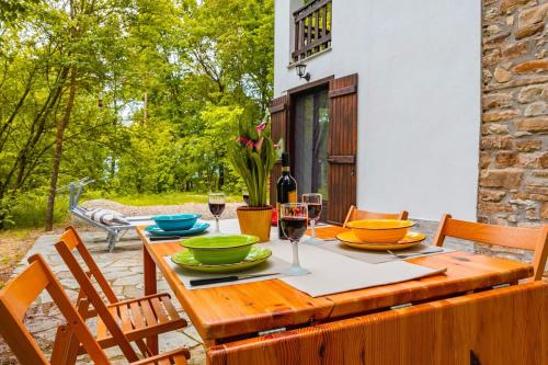 a wooden table with plates and wine glasses on a patio at La Quiete del Pero Fiorito Villa in the Langhe in Monastero Bormida