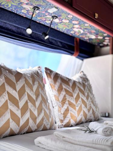 a bed with pillows on a bus at Riverside Retreat in a Luxe Caravan in Sabie