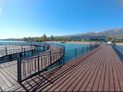 a wooden boardwalk on a beach with the water at Issyk Kul in Korumdy