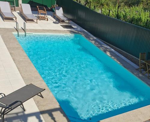 a swimming pool with blue water and chairs in it at HOUSE DOURO in Peso da Régua