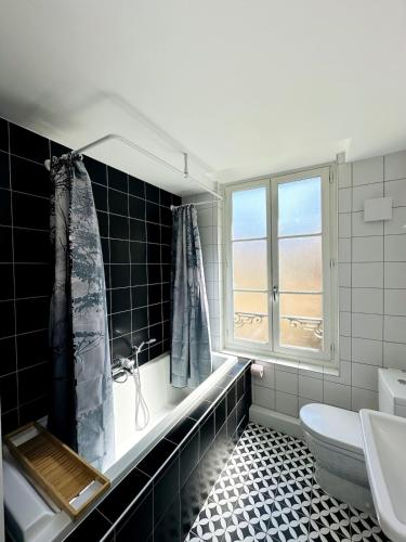 une salle de bain avec baignoire et toilettes et une fenêtre dans l'établissement Dijon Hypercentre Apartment, à Dijon