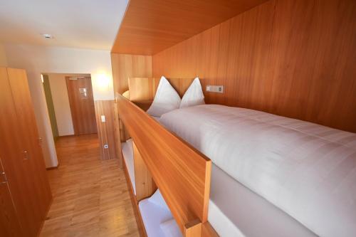 a bedroom with a large white bed with wooden walls at Bed & Breakfast Hostel Nives in Solda