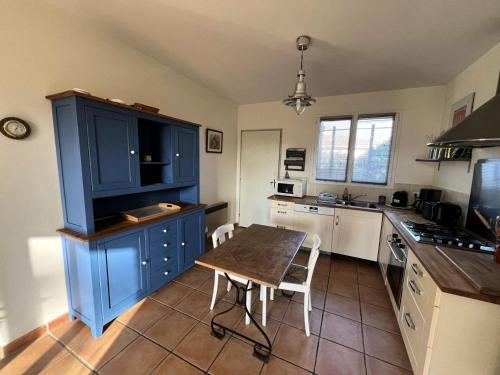 une cuisine avec des placards bleus et une table en bois dans l'établissement Résidence 121-montalivet - 121 - Agréable maison de vacances dans Montalivet MAE-4891, à Vendays-Montalivet
