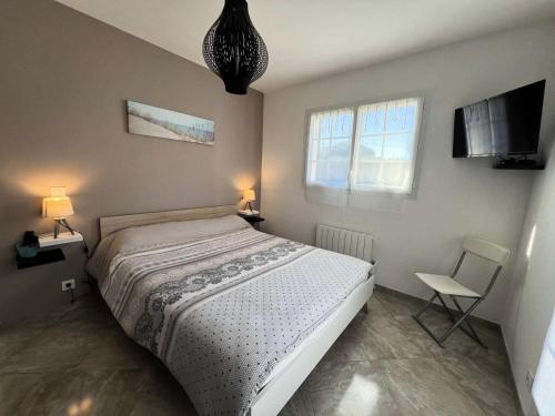 une chambre avec un lit, une télévision et une chaise dans l'établissement Résidence 118-montalivet - 118 - Maison décorée avec goût en plein cœur de Montalivet MAE-1181, à Vendays-Montalivet