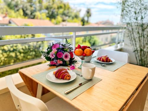 une table avec une assiette de nourriture et de fleurs sur un balcon dans l'établissement Cannes Breeze, à Cannes