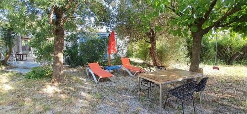 une table de pique-nique et des chaises sous un arbre dans l'établissement Lou Mazet, à Cabrières