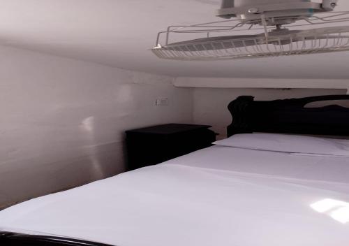 Hostal #10-33 في كارتاهينا دي اندياس: غرفة نوم مع سرير أبيض مع اللوح الأمامي الأسود