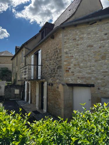 un vieux bâtiment en briques avec un portail et un balcon dans l'établissement Louhmari, à Sarlat-la-Canéda