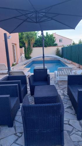 une terrasse avec des chaises et un parasol ainsi qu'une piscine dans l'établissement villa climatisée avec grande piscine, à Saint-Laurent-de-la-Salanque