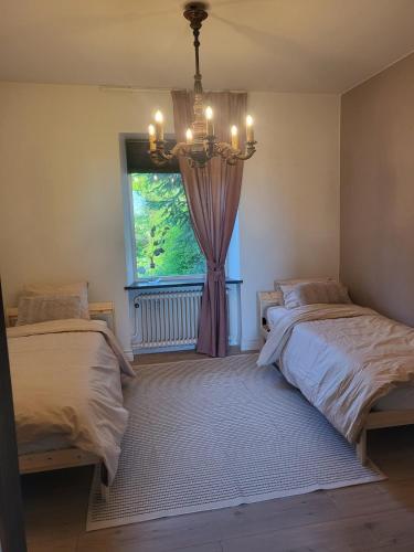 a bedroom with two beds and a window with a chandelier at Cosy and charming semi-detached house in Hilleshög in Härslöv