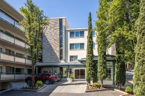an apartment building with a parking lot and trees at Park Lane Suites & Inn in Portland