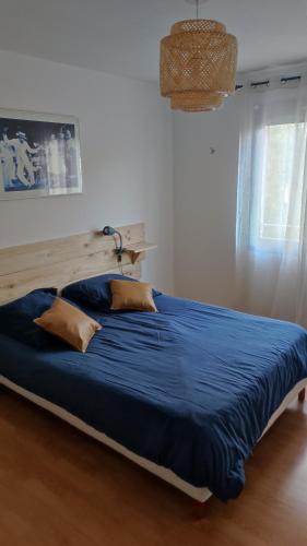 - un lit avec des draps et des oreillers bleus dans une chambre dans l'établissement Le Trident, à Fréjus