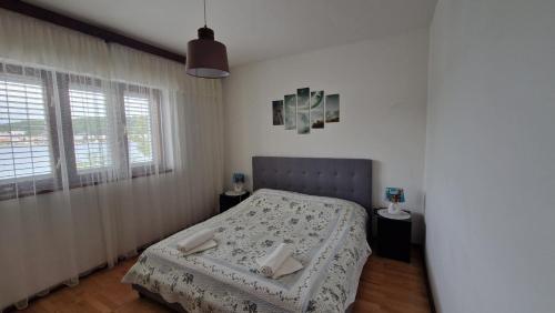a small bedroom with a bed and two windows at Apartment Vjera in Tisno