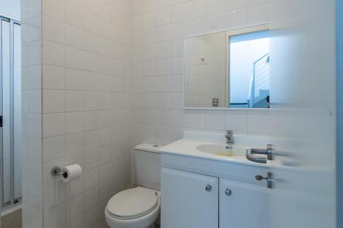 a white bathroom with a toilet and a sink at Luxury and tranquility facing the sea in Quintay