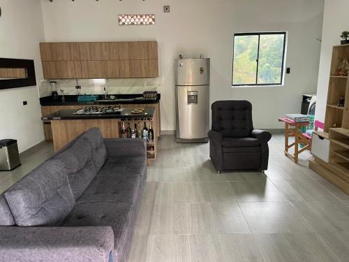 Una sala de estar con un sofá y una cocina. en Villa Paulina, en Ebéjico