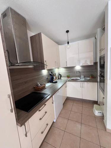 une cuisine avec des armoires blanches et un évier dans l'établissement Maison grand confort Port Camargue LE GRAU DU ROI proche ESPIGUETTE, au Grau-du-Roi