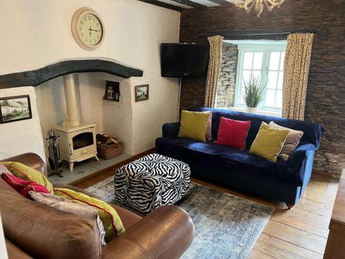 ein Wohnzimmer mit Sofa und Kamin in der Unterkunft Cosy North Devon Thatched Cottage near beaches in Marwood