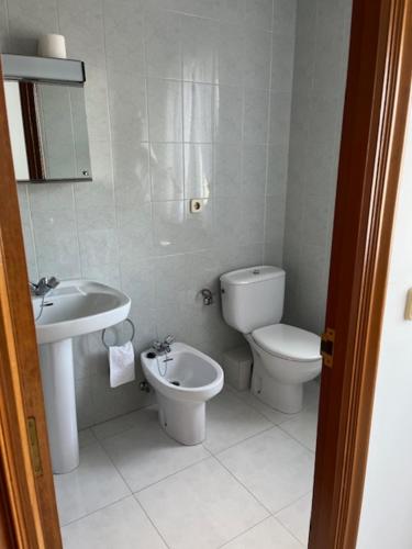 Un baño blanco con inodoro y lavabo. en Hostal Delfino, en Bardaos