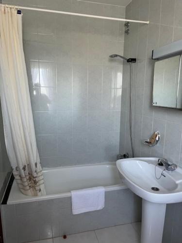 a bathroom with a tub and a sink and a shower at Hostal Delfino in Bardaos
