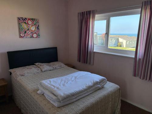 a small bed in a bedroom with a window at Bungalow 19 Widemouth Bay in Poundstock