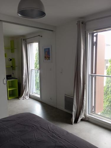 une chambre avec un lit et une grande fenêtre dans l'établissement Appartement 2 pièces entre centre ville et machine de l'île, à Nantes