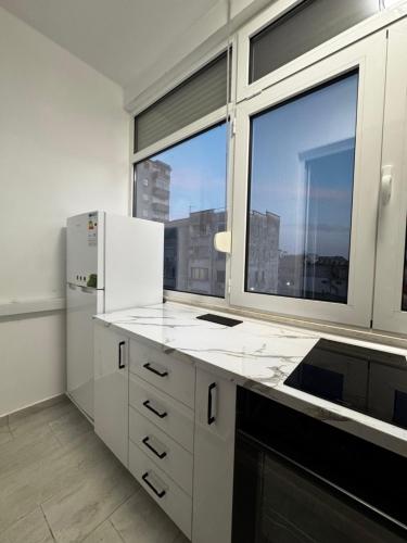 a kitchen with white cabinets and a large window at Mira's Apartment in Shkodër