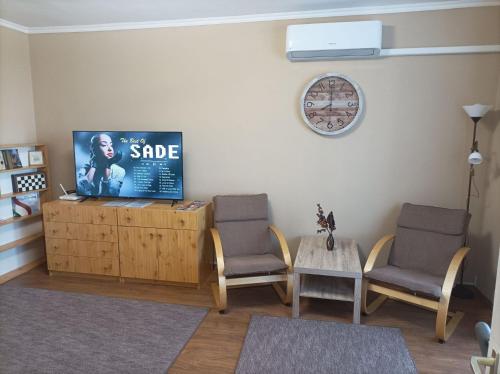 sala de estar con 2 sillas y TV en la pared en DebRentZen Station Apartman - business plus, en Debrecen