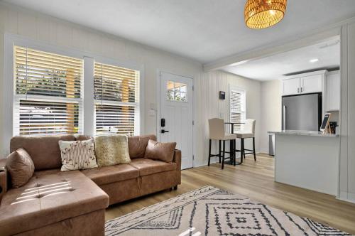 a living room with a brown couch and a kitchen at It's A Vibe- less than 10mins Capital,Hospitals,FAMU,&FSU in Tallahassee