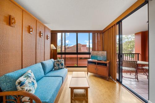 a living room with a blue couch and a balcony at Kahana Falls Resort in Honokowai