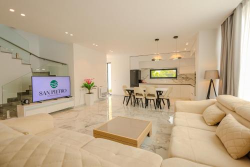 a living room with a white couch and a television at SanPietro Premium Villas in Draçi